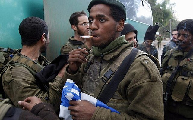 Un soldat israélien tient un drapeau national en fumant une cigarette près de la frontière Israël-Gaza après que son unité d'infanterie a quitté la bande de Gaza le 18 janvier 2009. (Menahem Kahana/AFP/Getty Images/via JTA)