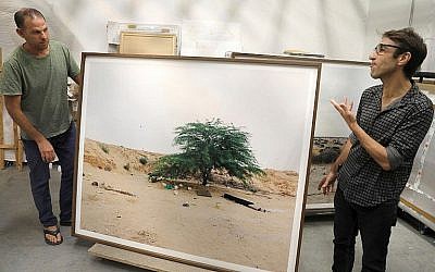 L'artiste-photographe Ron Amir (à gauche) et le conservateur Noam Gal aux côtés d'une photographie de l'exposition "Quelque part dans le désert", dans une salle du musée d'ISraël, en juillet 2018. (Crédit : AFP/Menahem Kahana)