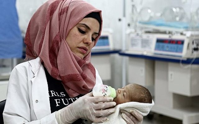 Malaké Harbaliyya, infirmière de 31 ans,tient dans ses bras un enfant à "l'hôpital de l'Espoir" dans le village rebelle d'Al-Ghandoura, dans la province d'Alep (nord), le 1er août 2018. (Crédit : AFP/Nazeer AL-KHATIB)