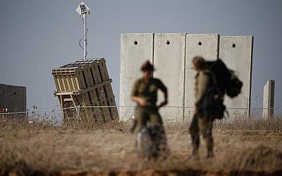 Des soldats israéliens marchent près d'un système de défense Iron Dome, conçu pour intercepter et détruire les roquettes à courte portée et les obus d'artillerie, dans la ville de Sderot, dans le sud d'Israël, le 9 août 2018. (Crédit : AFP PHOTO / Jack GUEZ)