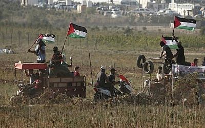 Des manifestants palestiniens portent des pneus à brûler lors d'un rassemblement le long de la frontière entre Israël et la bande de Gaza, à l'est de la ville de Gaza, le 17 août 2018. (AFP PHOTO / MAHMUD HAMS)