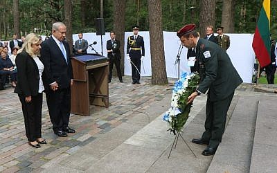 Le Premier ministre israélien Israel Benjamin Netanyahu et son épouse Sara se recueillent durant une cérémonie de dépose de gerbe au mémorial de la Shoah de Paneriai, à proximité de Vilnius, le 24 août 2018 (Crédit :/ AFP PHOTO / Petras Malukas)