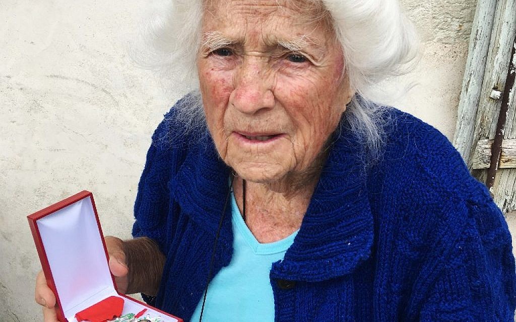 Genevieve Callerot, 102 ans pose avec sa Légion d'honneur dans le jardin de sa ferme, à Saint-Aulaye, dans le sud-ouest de la France, le 25 août 2018 (Crédit : AFP / MEHDI FEDOUACH)