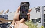 Une Israélienne utilise son iPhone devant l'immeuble du groupe israélien NSO, le 28 août 2016 à Herzliya, près de Tel Aviv. (AFP PHOTO / JACK GUEZ)