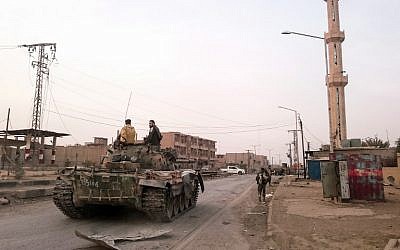 Des membres des forces gouvernementales pro-syriennes conduisent un char dans une rue de la ville syrienne d'Albu Kamal, le 20 novembre 2017. (AFP / STRINGER)