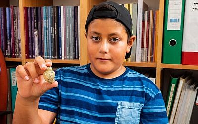 Itamar Barnea, 10 ans, avec une figurine de 11 500 ans trouvée en haute-Galilée en 2016. Une photo prise en août  2018. (Crédit : Assaf Peretz/Israel Antiquities Authority)