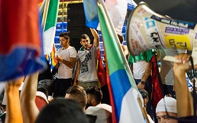Des manifestants brandissent des drapeaux israéliens et druzes lors d'une manifestation contre la loi sur l'Etat-nation à Tel Aviv, le 4 août 2018 (Crédit : Luke Tress / Times of Israel staff)