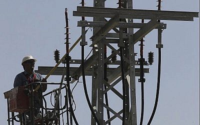 Image illustrant un employé de Israël Electricity Corporation soulevé par une grue au niveau d'un poteau de services publics pour effectuer des travaux de maintenance le 10 juin 2013. (Flash 90)