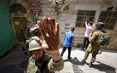 Photo d'illustration. Un soldat israélien tente de bloquer la prise de vue d'un photographe lors de la recherche d'hommes palestiniens dans la ville de Hébron, en Cisjordanie, le 22 juin 2017 (Crédit : Wisam Hashlamoun/Flash90)