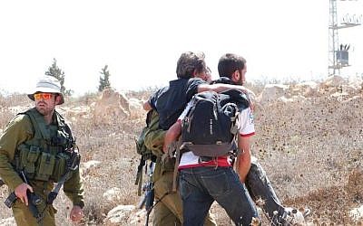 Un militant de gauche escorté par l'armée israélienne à proximité de l'implantation de Mitzpeh Yair, en Cisjordanie, le 25 août 2018 (Crédit : BTselem)