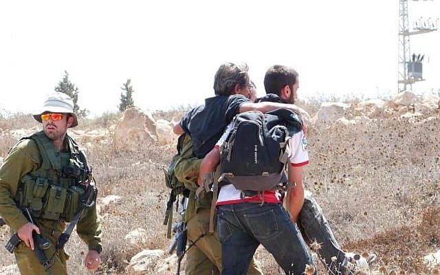 Un militant de gauche escorté par l'armée israélienne à proximité de l'implantation de Mitzpeh Yair, en Cisjordanie, le 25 août 2018 (Crédit : BTselem)