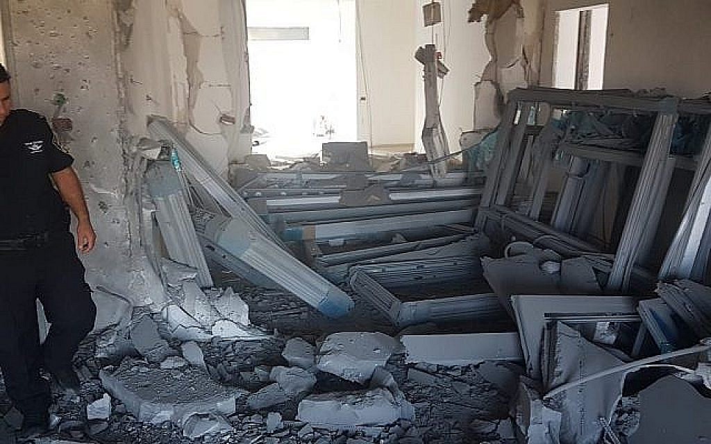 Un officier de police inspecte les dégâts sur un chantier de construction dans la ville de Sdérot, au sud d’Israël, près de la frontière de Gaza, suite à une salve de roquettes, le 9 août 2018. (Crédit : Police israélienne)