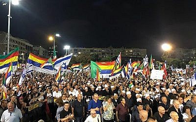 Des manifestants brandissent des drapeaux israéliens et druzes lors d'une manifestation contre la loi sur l'Etat-nation organisée à Tel Aviv, le 4 août 2018 (Crédit : Luke Tress / Times of Israel staff)