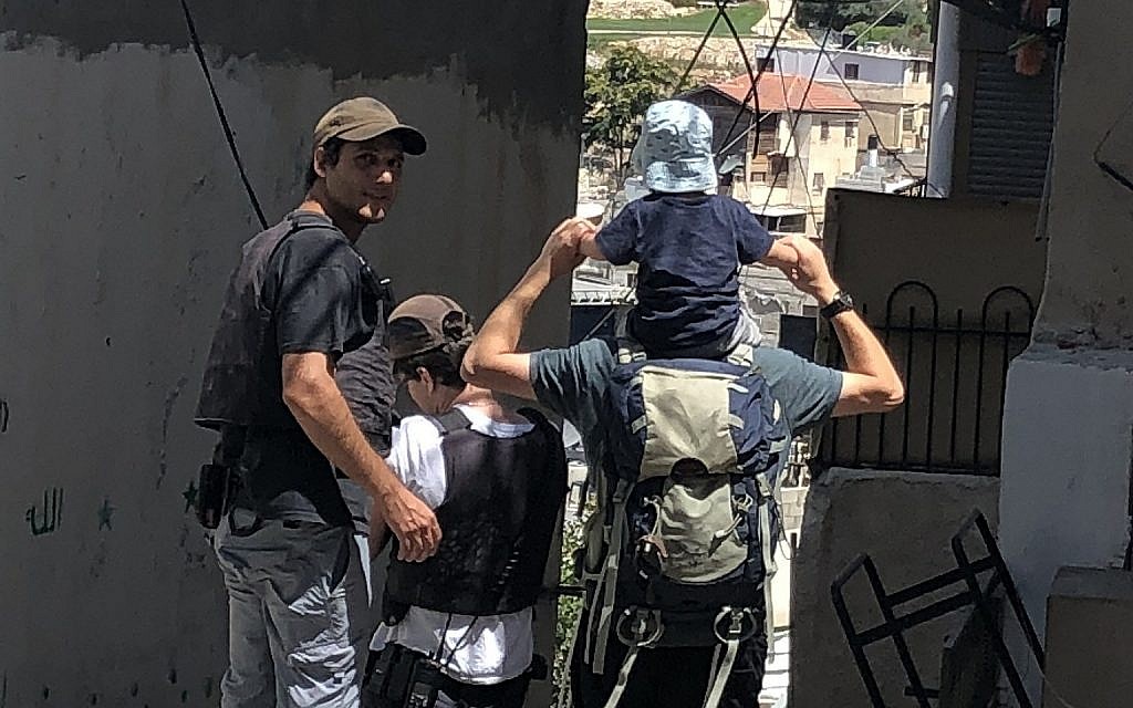 Des gardes de sécurité privés financés par l'Etat escortent une famille juive à la maison Beit Rachel, appartenant à Ateret Cohanim dans le quartier de Batan al-Hawa de Silwan, à Jérusalem Est, le 31 juillet 2018 (Crédit : Sue Surkes/Times of Israel.)