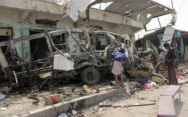 Les Yéménites réunis autour d'un bus détruit sur le site d'une frappe aérienne de la coalition menée par les saoudiens qui a visé le marché de Dahyan la veille dans la province de Saada, bastion des Houthis, le 10 août 2018 (Crédit : AFP PHOTO / -)