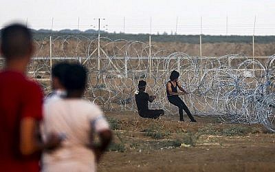 Les Palestiniens tirent un câble attaché à un fil barbelé pour essayer de détruire une section de la clôture de sécurité entre la bande de Gaza et Israël, durant des affrontements survenus à l'est de Gaza City, le 7 septembre 2018 (Crédit : AFP/Said Khatib)