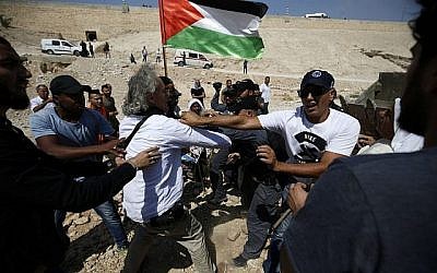 Les forces de sécurité israéliennes se bagarrent avec le manifestant franco-américain Frank Romano, le 14 septembre 2018, durant une manifestation contre la destruction du village bédouin de Khan al-Ahmar, en Cisjordanie (Crédit : AFP PHOTO / ABBAS MOMANI)