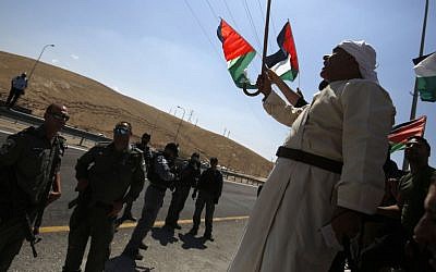 Des manifestants palestiniens brandissent le drapeau national devant les soldats israéliens pendant une manifestation contre le plan de démolition israélien du village bédouin de Khan al-Ahmar, en Cisjordanie, le 14 septembre 2018 (Crédit :AFP PHOTO / ABBAS MOMANI)