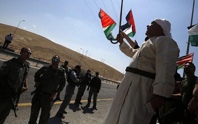 Des manifestants palestiniens brandissent le drapeau national devant les soldats israéliens pendant une manifestation contre le plan de démolition israélien du village bédouin de Khan al-Ahmar, en Cisjordanie, le 14 septembre 2018 (Crédit :AFP PHOTO / ABBAS MOMANI)
