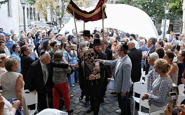Le rabbin Asher Faith transporte un rouleau de Torah tout juste consacré pour la congrégation, lors de la consécration de l'espace de prière de la synagogue médiévale de Budapest, le 6 septembre 2018 (Crédit : Márton Merész) Le rabbin Asher Faith transporte un rouleau de Torah tout juste consacré pour la congrégation, lors de la consécration de l'espace de prière de la synagogue médiévale de Budapest, le 6 septembre 2018 (Crédit : Márton Merész)