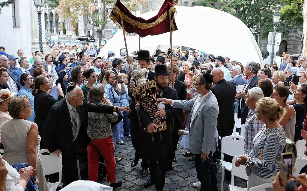 Le rabbin Asher Faith transporte un rouleau de Torah tout juste consacré pour la congrégation, lors de la consécration de l'espace de prière de la synagogue médiévale de Budapest, le 6 septembre 2018 (Crédit : Márton Merész)