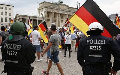 Des partisans de l'AfD allemande brandissent des drapeaux devant la porte de Brandenburg à Berlin, en Allemagne, le 27 mai 2018 (Crédit : AP Photo/Michael Sohn)