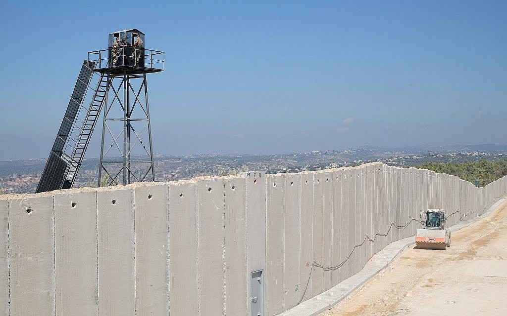 Un véhicule de construction israélien passe à côté d'un mur de béton en construction le long de la "Ligne bleue" séparant Israël et le Liban, alors que des membres des Forces armées libanaises observent depuis une tour de garde, près de la ville israélienne de Rosh Hanikra, le 5 septembre 2018. (Crédit : Judah Ari Gross/Times of Israel) Un véhicule de construction israélien passe à côté d'un mur de béton en construction le long de la "Ligne bleue" séparant Israël et le Liban, alors que des membres des Forces armées libanaises observent depuis une tour de garde, près de la ville israélienne de Rosh Hanikra, le 5 septembre 2018. (Crédit : Judah Ari Gross/Times of Israel)