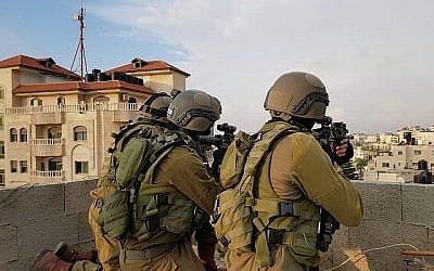 Les soldats israéliens arrêtent un homme palestinien soupçonné d'avoir tué un soldat en jetant une pierre qui l'a atteint à la tête au camp de réfugiés d'Am-Amari à Ramallah, la veille, le 6 juin 2018 (Crédit  : Armée israélienne)