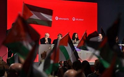 Des délégués à la conférence du Parti travailliste à Liverpool brandissent des drapeaux palestiniens pendant un débat, le 25 septembre 2018, sous le regard du leader Jeremy Corbyn depuis le podium. (Crédit : Oli Scarff/AFP)