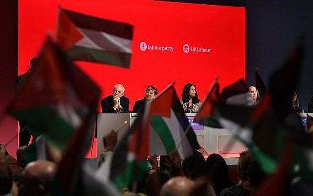 Des délégués à la conférence du Parti travailliste à Liverpool brandissent des drapeaux palestiniens pendant un débat, le 25 septembre 2018, sous le regard du leader Jeremy Corbyn depuis le podium. (Crédit : Oli Scarff/AFP) Des délégués à la conférence du Parti travailliste à Liverpool brandissent des drapeaux palestiniens pendant un débat, le 25 septembre 2018, sous le regard du leader Jeremy Corbyn depuis le podium. (Crédit : Oli Scarff/AFP)
