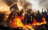 Des émeutiers palestiniens brandissent un drapeau près du littoral au nord de la bande de Gaza le 22 octobre  2018. (Crédit : MAHMUD HAMS / AFP)