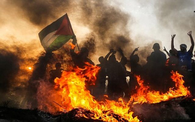 Des émeutiers palestiniens brandissent un drapeau près du littoral au nord de la bande de Gaza le 22 octobre  2018. (Crédit : MAHMUD HAMS / AFP)