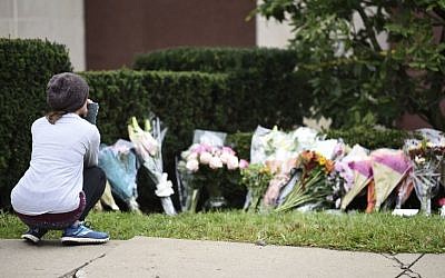 Une femme regarde les fleurs d'un mémorial aux abords de la synagogue Tree of Life de Pittsburgh, aux Etats-Unis, au lendemain d'une fusillade meurtrière, le 28 octobre 2018 (Crédit : Brendan SMIALOWSKI/AFP)
