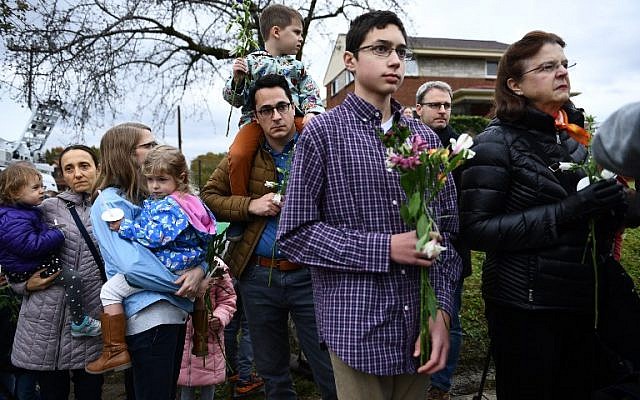 Des gens rendent un dernier hommage à un mémorial dressé en souvenir des onze  victimes d'une fusillade survenue le 27 octobre dans la synagogue Tree of life de Pittsburgh, dans le quartier de Squirrell Hill, le 28 octobre 2018 (Crédit :  Brendan Smialowski / AFP)