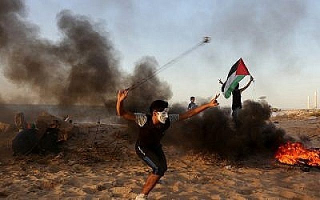 Un Palestinien jette des pierres sur des soldats israéliens lors d'une émeute sur la plage près de la frontière maritime avec Israël, à Beit Lahia, dans le nord de la bande de Gaza, le 29 octobre 2018. (MAHMUD HAMS / AFP)