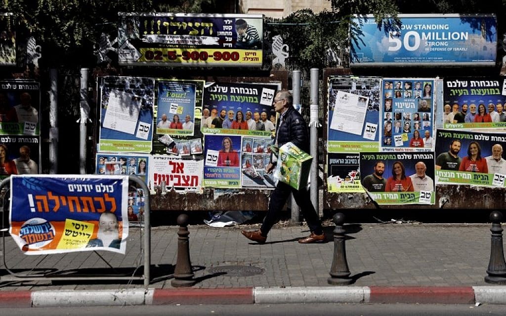 Un Israélien accroche des affiches de campagne pour les élections locales dans le centre de Jérusalem le 30 octobre 2018. (Crédit : THOMAS COEX / AFP)