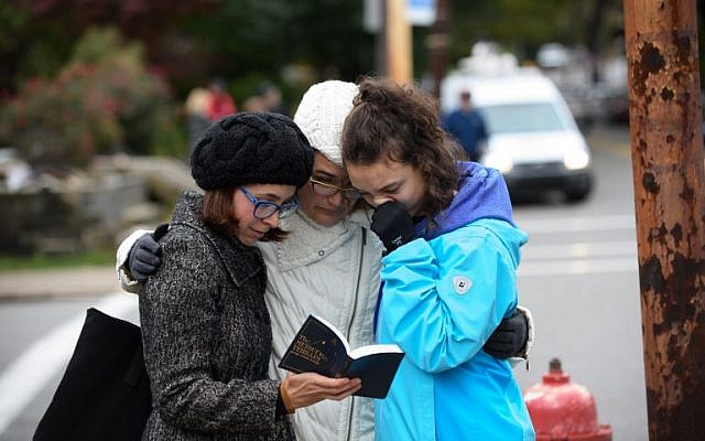 Tammy Hepps, Kate Rothstein et sa fille de 16 ans Simone Rothstein, prient aux abords du site d'une fusillade meurtrière à la synagogue Tree of Life du quartier Squirrel Hill à Pittsburgh, Pennsylvanie, le 27 octobre 2018 (Crédit : Jeff Swensen/Getty Images/AFP)