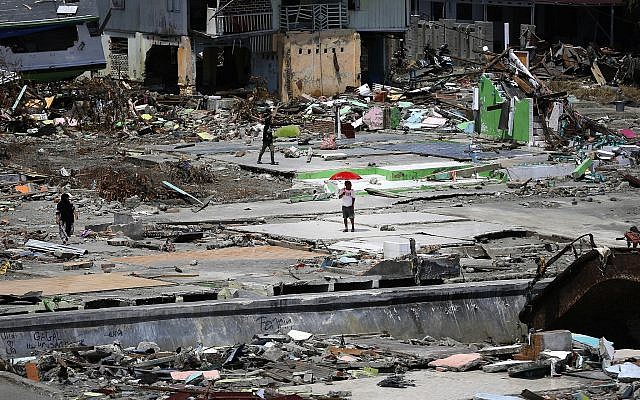 Un homme sous un parapluie dans un quartier du village de Wani, dans la banlieue de Palu, dans le centre de Sulawesi, en Indonésie, le 4 octobre 2018 (Crédit : Dita Alangkara/AP) Un homme sous un parapluie dans un quartier du village de Wani, dans la banlieue de Palu, dans le centre de Sulawesi, en Indonésie, le 4 octobre 2018 (Crédit : Dita Alangkara/AP)