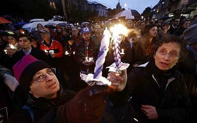 Des gens allument des bougies alors qu'ils se rassemblent pour une veillée suite à une fusillade mortelle contre la congrégation de Tree of Life, dans le quartier de Squirrel Hill à Pittsburgh, le samedi 27 octobre 2018. (Crédit : AP / Matt Rourke)