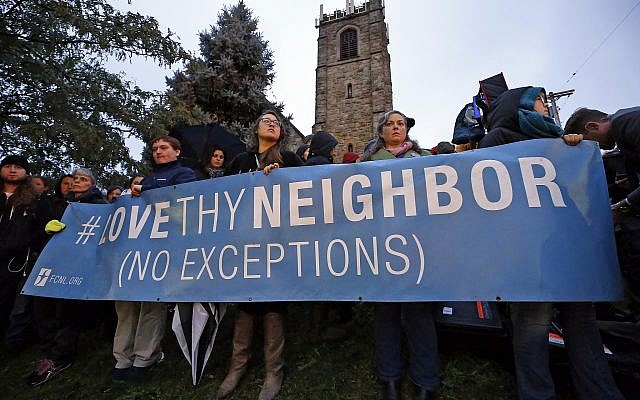 Un groupe tient une pancarte à l'intersection de Murray Ave. et Forbes Ave. dans le quartier de Squirrel Hill à Pittsburgh lors d'une veillée commémorative en l'honneur des victimes de la fusillade de la synagogue de Tree of life, où un tireur a ouvert le feu, faisant 11 morts et six blessés, dont quatre policiers, samedi 27 octobre 2018. (Crédit : AP Photo / Gene J. Puskar)