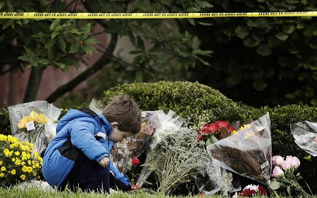 Gideon Murphy place des fleurs aux abords de la synagogue Tree of Life de Pittsburgh, aux Etats-Unis, au lendemain d'une fusillade meurtrière, le 28 octobre 2018 (Crédit : AP Photo/Matt Rourke)