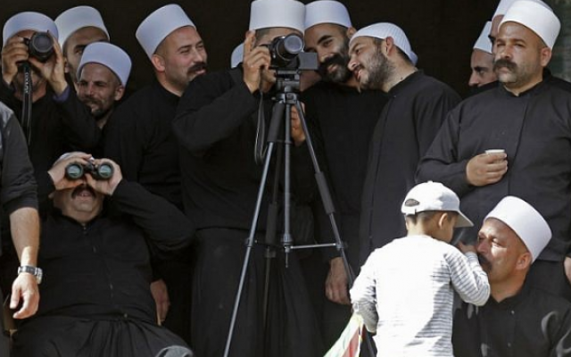 Des membres de la communauté druze examinent avec des jumelles et des caméras depuis leur village de Majdal Shams, situé sur les hauteurs du Golan, l'autre côté de la frontière, à la recherche d'autres membres de la communauté du côté syrien, lors d'une manifestation organisée le 6 octobre 2018 pour commémorer le 45e anniversaire de la guerre israélo-arabe 1973 (AFP PHOTO / JALAA MAREY)