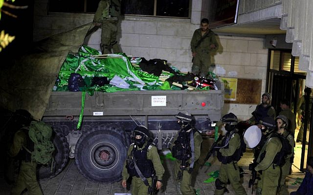 Des soldats israéliens sont en train de charger des drapeaux du Hamas lors d'une patrouille à l'Université de Birzeit, à la périphérie de la ville de Ramallah, en Cisjordanie, lors d'une opération le 19 juin 2014. (Issam Rimawi/Flash90)