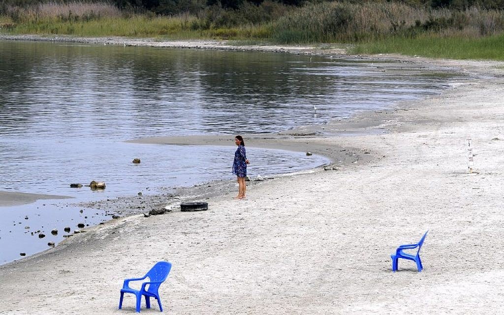 Une femme se tient sur la plage de sable du lac de Tibériade., le 8 ocotbre 2018 Les étendues de sable  sont apparues à cause d'une baisse de niveau de l'eau, attribuée à une surexploitation des ressources. (Crédit : JACK GUEZ / AFP)