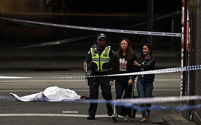 un policier écarte les passants de la scène d'une attaque au couteau, devant le corps de la victime, recouvert d'un drap blanc, à Melbourne, le 9 novembre 2018 (Crédit : WILLIAM WEST / AFP) un policier écarte les passants de la scène d'une attaque au couteau, devant le corps de la victime, recouvert d'un drap blanc, à Melbourne, le 9 novembre 2018 (Crédit : WILLIAM WEST / AFP)