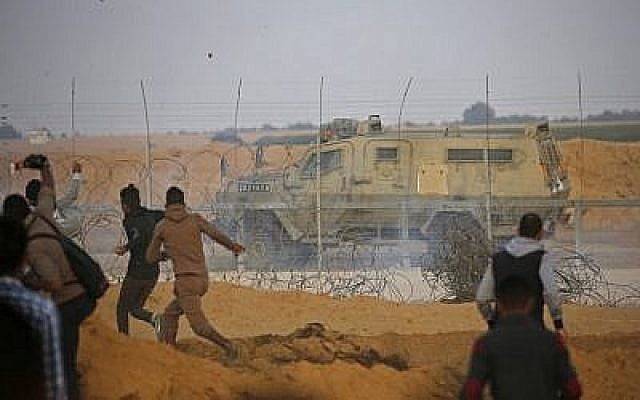 Des Palestiniens jettent des pierres sur un véhicule militaire pendant une manifestation à proximité de la frontière entre Israël et Khan Yunès dans le sud de la bande de Gaza, le 9 novembre 2018 (Crédit : Said KHATIB / AFP)