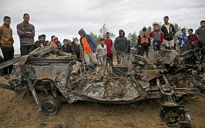 Des Palestiniens autour des décombres d'une voiture qui aurait été détruite par une frappe israélienne à Khan Younès, dans le sud de la bande de Gaza, le 12 novembre 2018. (Crédit : SAID KHATIB / AFP)