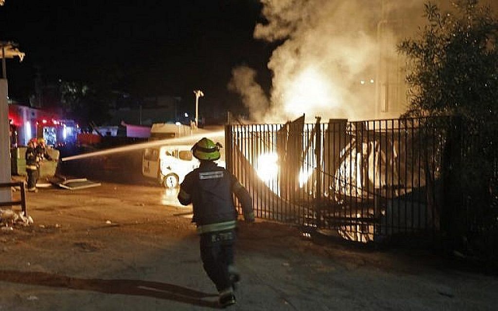 Les forces de sécurité et les pompiers israéliens se rassemblent près d'un bâtiment incendié après avoir été touché par une roquette tirée depuis la bande de Gaza, dans la ville de Sderot, dans le sud du pays, le 12 novembre 2018. (Crédit : Menahem KAHANA / AFP)