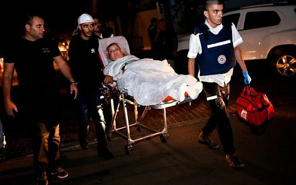 Une femme israélienne blessée, évacuée de son appartement incendié après avoir été touché par une roquette tirée depuis la bande de Gaza, est escortée à l'hôpital sur une civière dans la ville d'Ashkelon, dans le sud d'Israël, le 12 novembre 2018. (Crédit : GIL COHEN-MAGEN / AFP)
