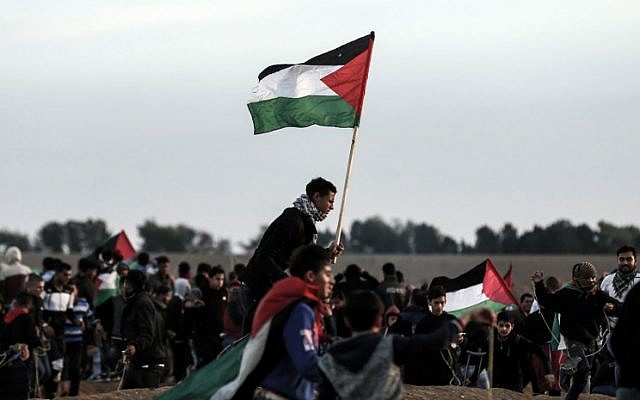 Des émeutiers palestiniens brandissent des drapeaux dans la banlieue est de Gaza City, le 23 novembre 2018. (Crédit : MAHMUD HAMS / AFP)